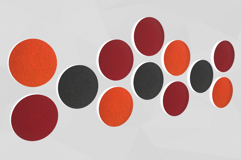 12 absorbeurs acoustiques colorés en forme de cercle (soni ELEMENT CIRCLE) placés sur un mur de différentes couleurs.