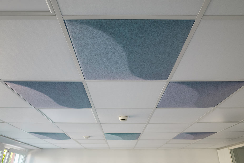 Ausschnitt einer handelsüblichen Rasterdecke mit eingelegten Akustikabsorbern soni COMFORT SD in Weiß und soni COLOR Design in Blau.