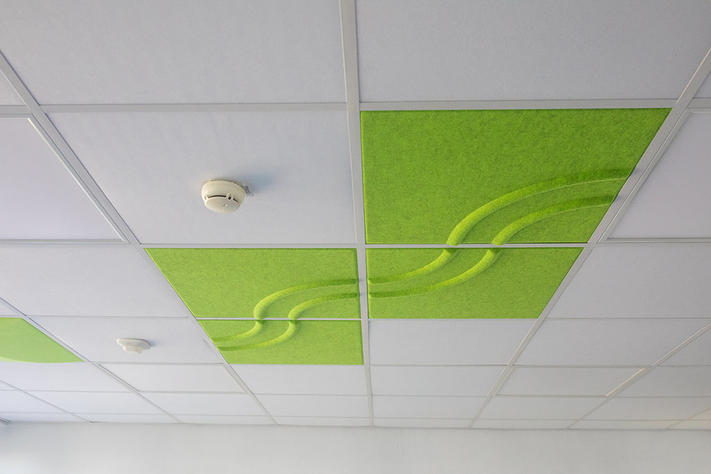 Ausschnitt einer handelsüblichen Rasterdecke mit eingelegten Akustikabsorbern soni COMFORT SD in Weiß und soni COLOR Design in Grün.