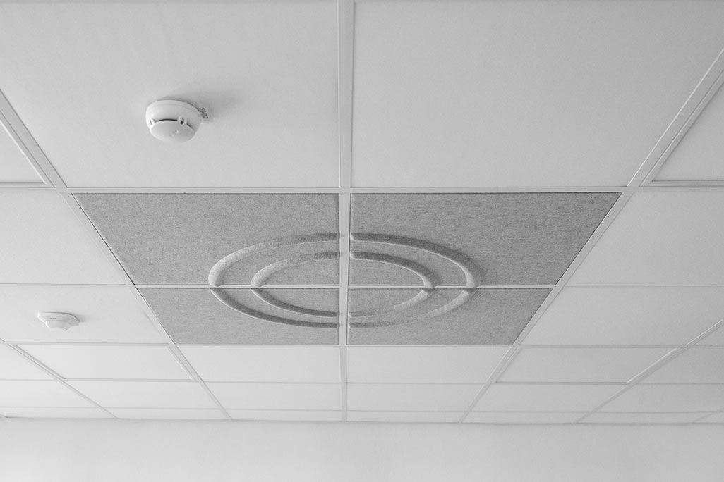 Ausschnitt einer handelsüblichen Rasterdecke mit eingelegten Akustikabsorbern soni COMFORT SD in Weiß und soni COLOR Design in Hellgrau.
