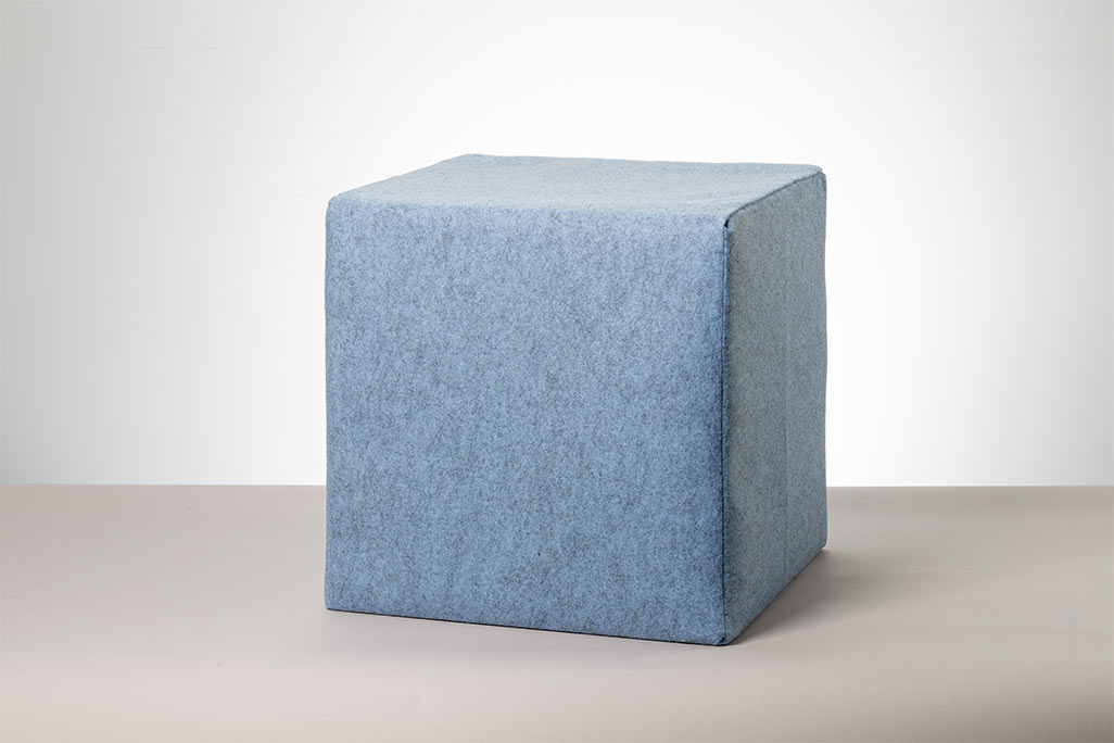 Blauer Sitzwürfel vor weißem Hintergrund fotografiert.