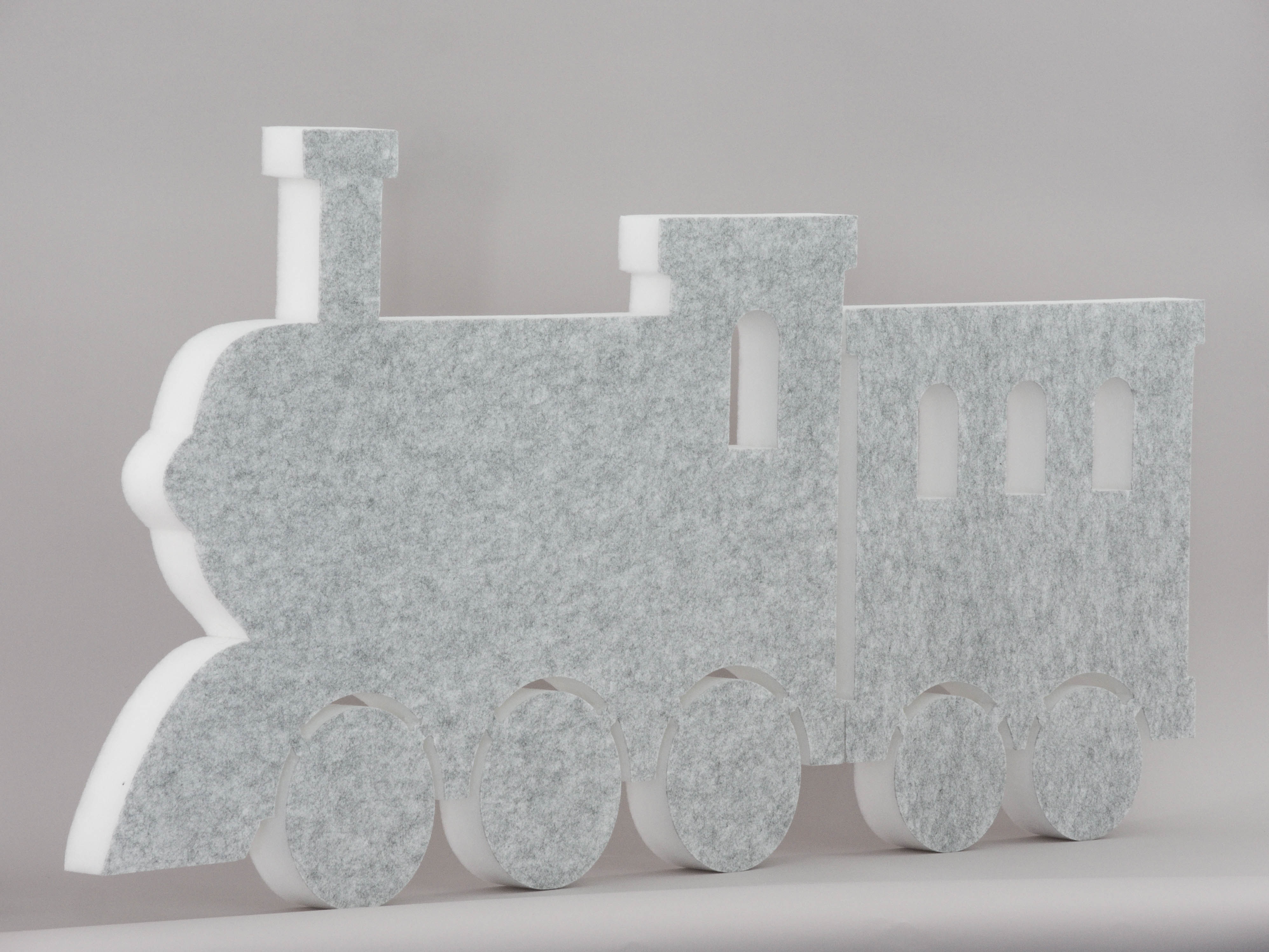 Schallabsorber in Form einer Lokomotive und einem Waggon (soni ELEMENT TRAIN) in der Farbe Hellgrau vor grauem Hintergrund diagonal fotografiert