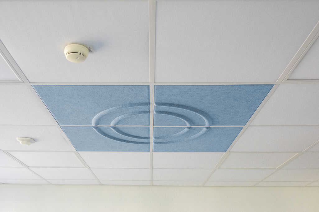 Ausschnitt einer handelsüblichen Rasterdecke mit eingelegten Akustikabsorbern soni COMFORT SD in Weiß und soni COLOR Design in Blau.