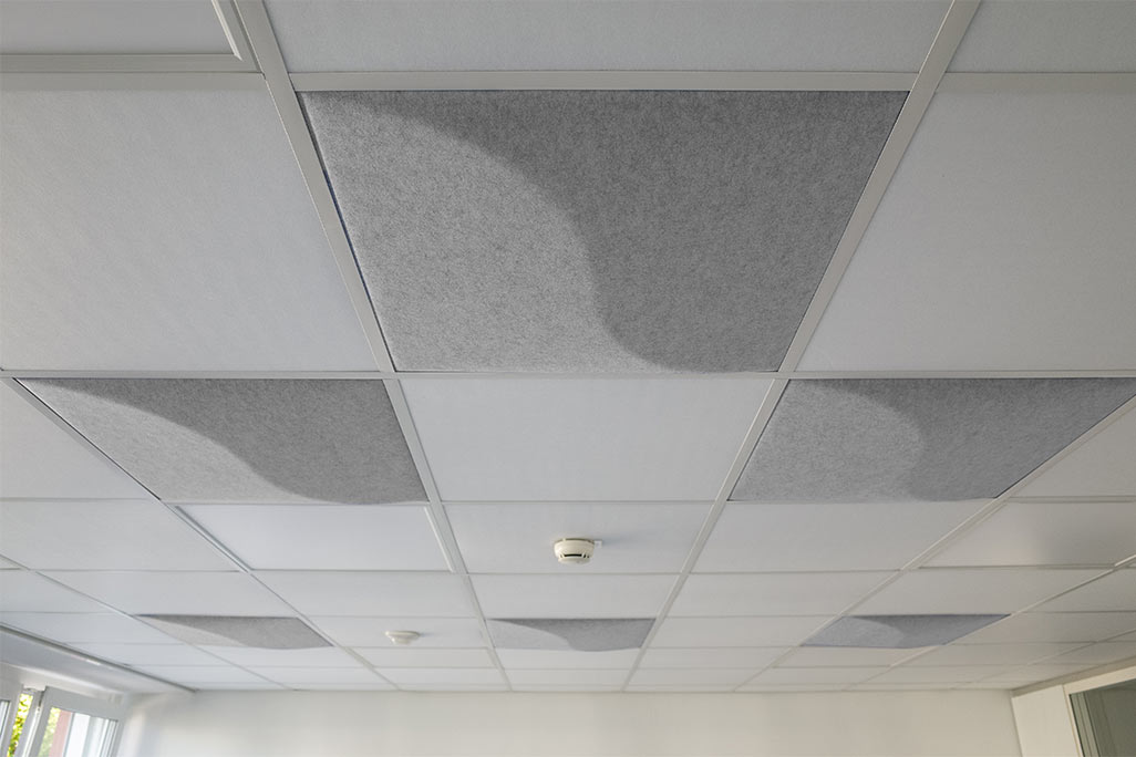 Découpe d'un plafond modulaire du commerce avec des absorbeurs acoustiques soni COMFORT SD en blanc et soni COLOR Design insérés.