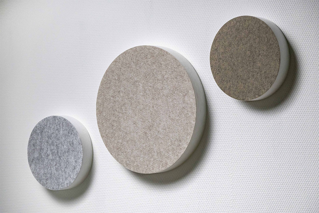Trois absorbeurs acoustiques en forme de cercle (soni ELEMENT CIRCLE) sur un mur blanc dans les couleurs greige, gris clair et beige.