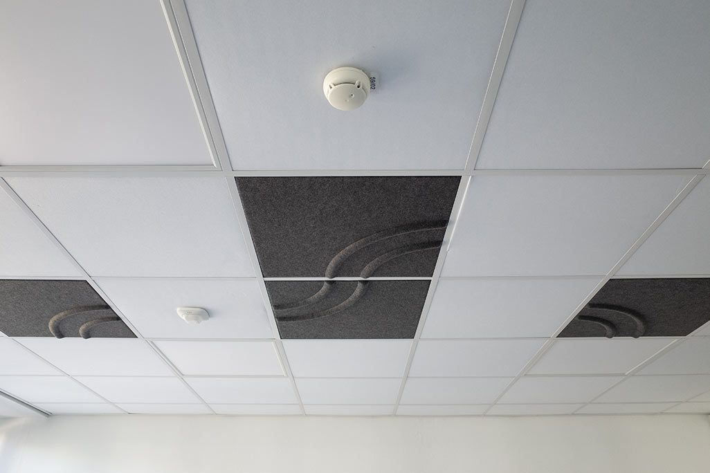 Ausschnitt einer handelsüblichen Rasterdecke mit eingelegten Akustikabsorbern soni COMFORT SD in Weiß und soni COLOR Design in Anthrazit.